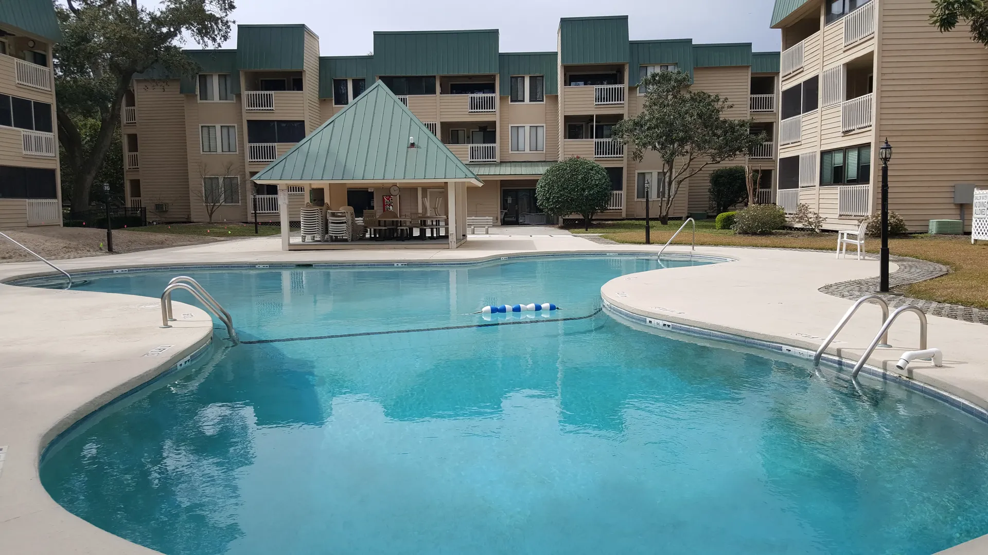 One of the two outdoor pools at The Spa, with a green-roof pavilion and lounge chairs